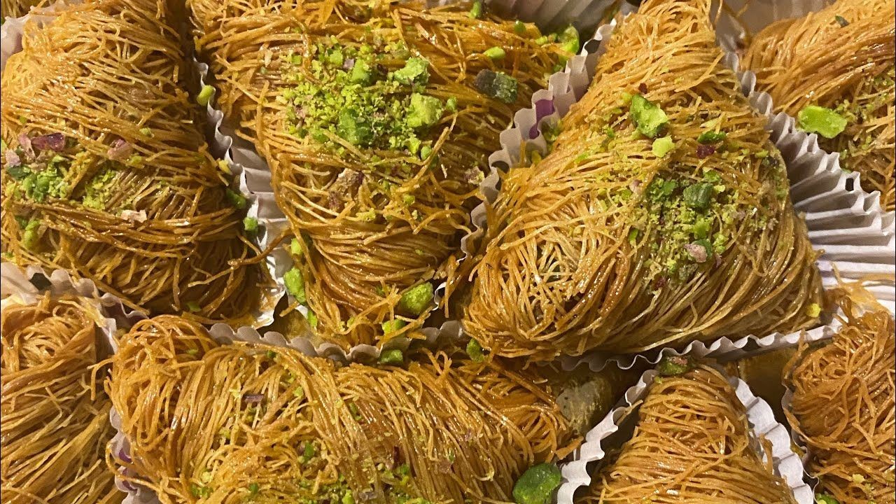 Close-up of traditional Middle Eastern pastries with shredded dough and pistachio garnish.